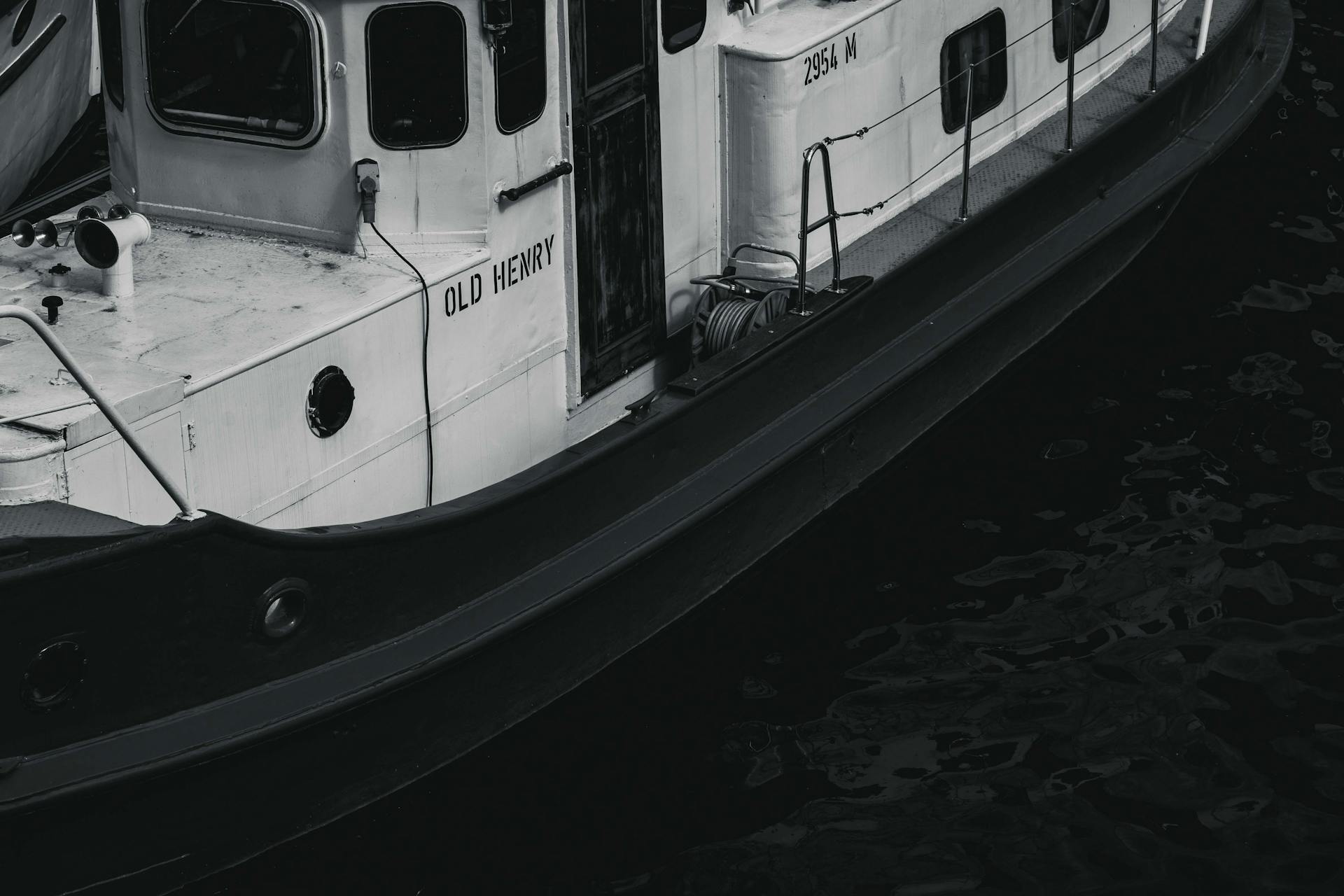 Monochrome image of the vintage tugboat 'Old Henry' docked in shadowy waters.