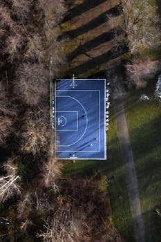 Drone shot of a basketball court surrounded by trees in Graz, Austria.