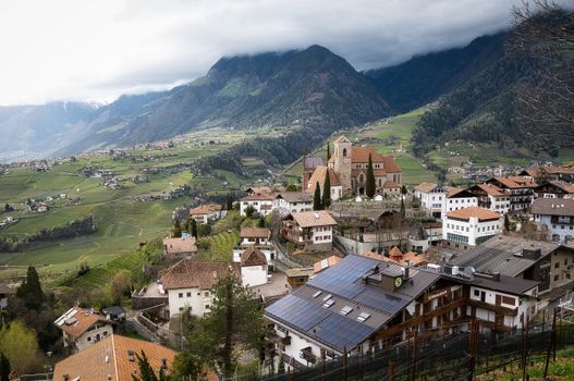 Picturesque panorama of Schenna village, with lush vineyards and mountain backdrop in South Tyrol, Italy.