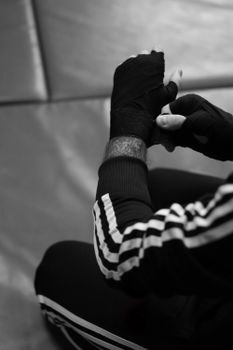 Detailed black and white view of an athlete wrapping hands before training.