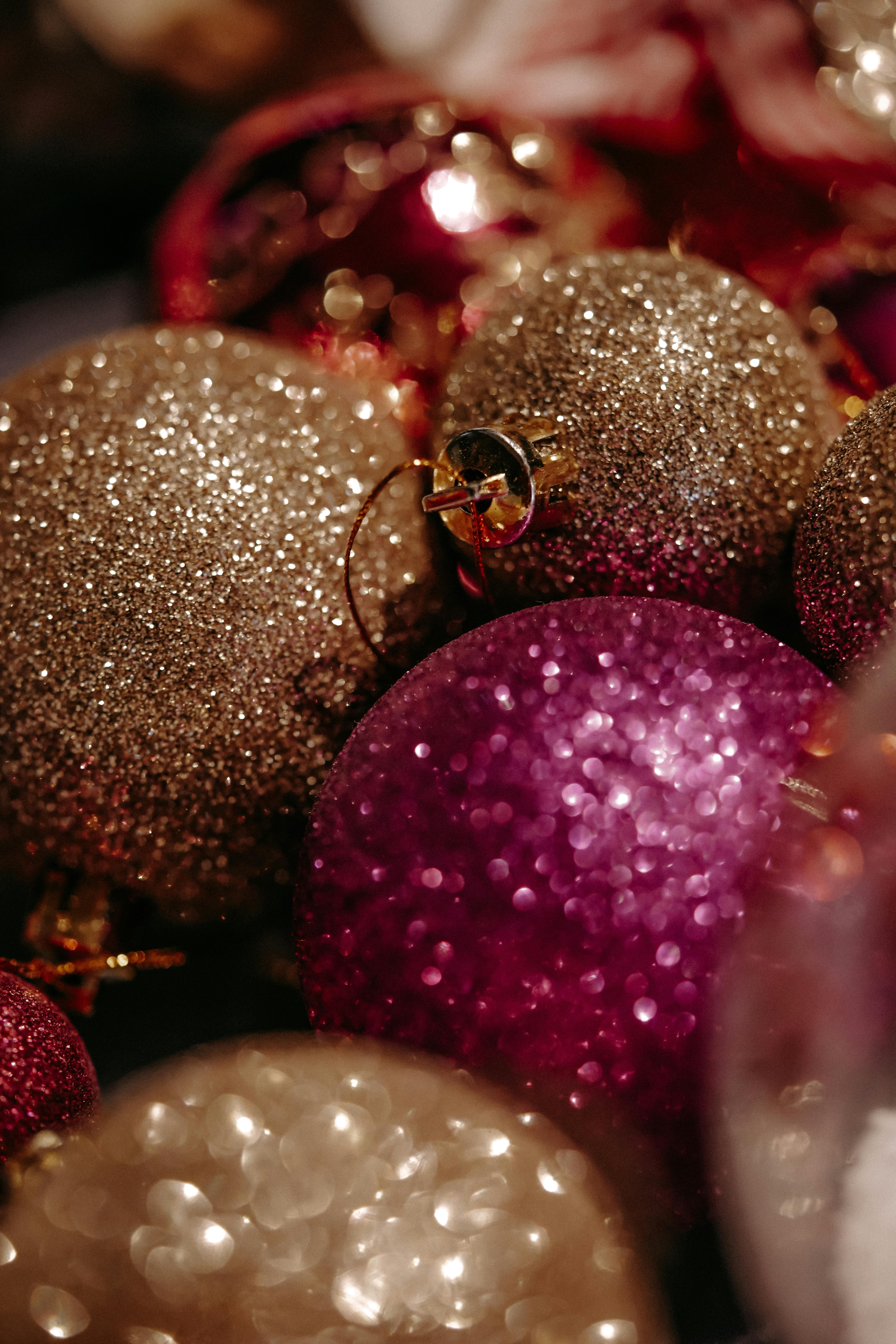 Festive glittering Christmas baubles with warm hues and sparkling bokeh for holiday decor.