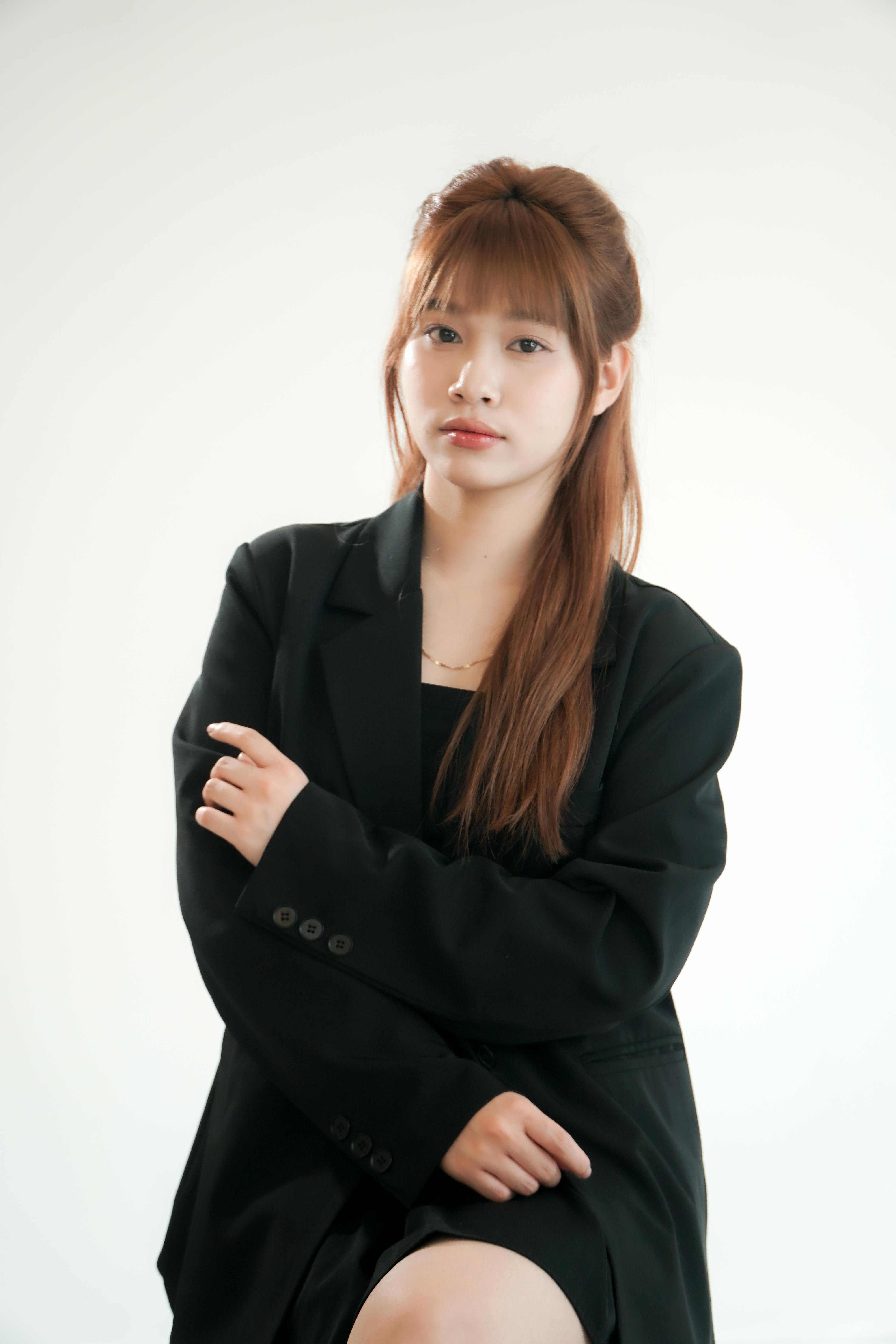 Portrait of a confident young woman wearing a black suit in a minimalist studio.