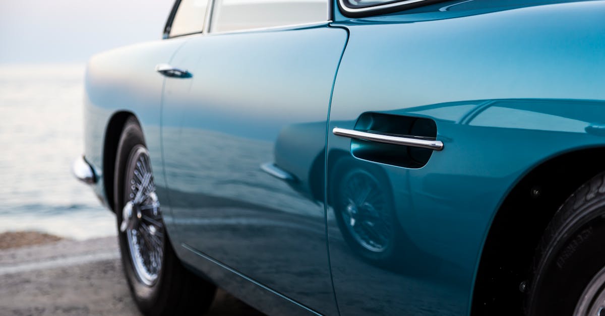 A classic vintage car with polished blue paint near the calm seaside at Marbella, Spain.