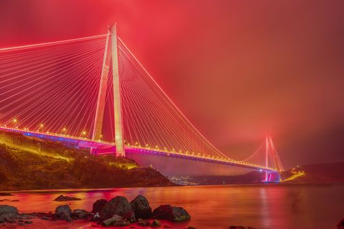 Free A stunning view of the Yavuz Sultan Selim Bridge glowing under vibrant red lights, spanning the Bosphorus Strait at night. Stock Photo