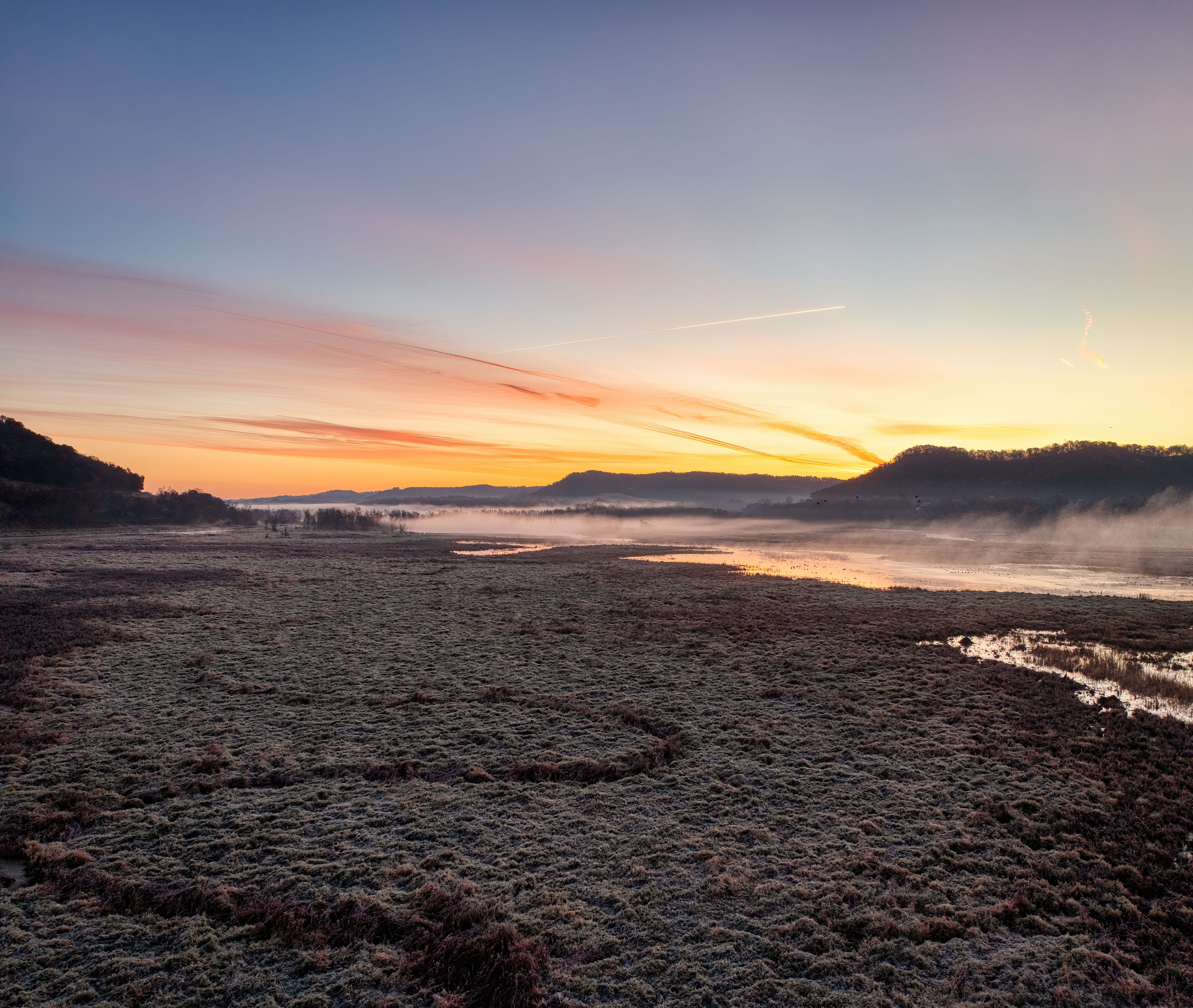A serene sunrise over misty fields in Alma, Wisconsin, showcasing nature's beauty.