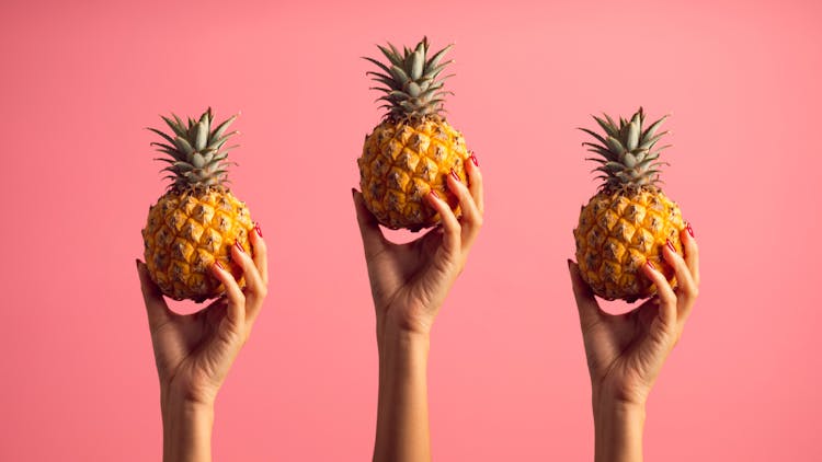 Person Holding Pineapples