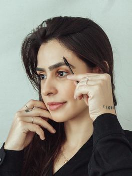 Close-up of a woman brushing her eyebrows, focusing on self-care and beauty routine.