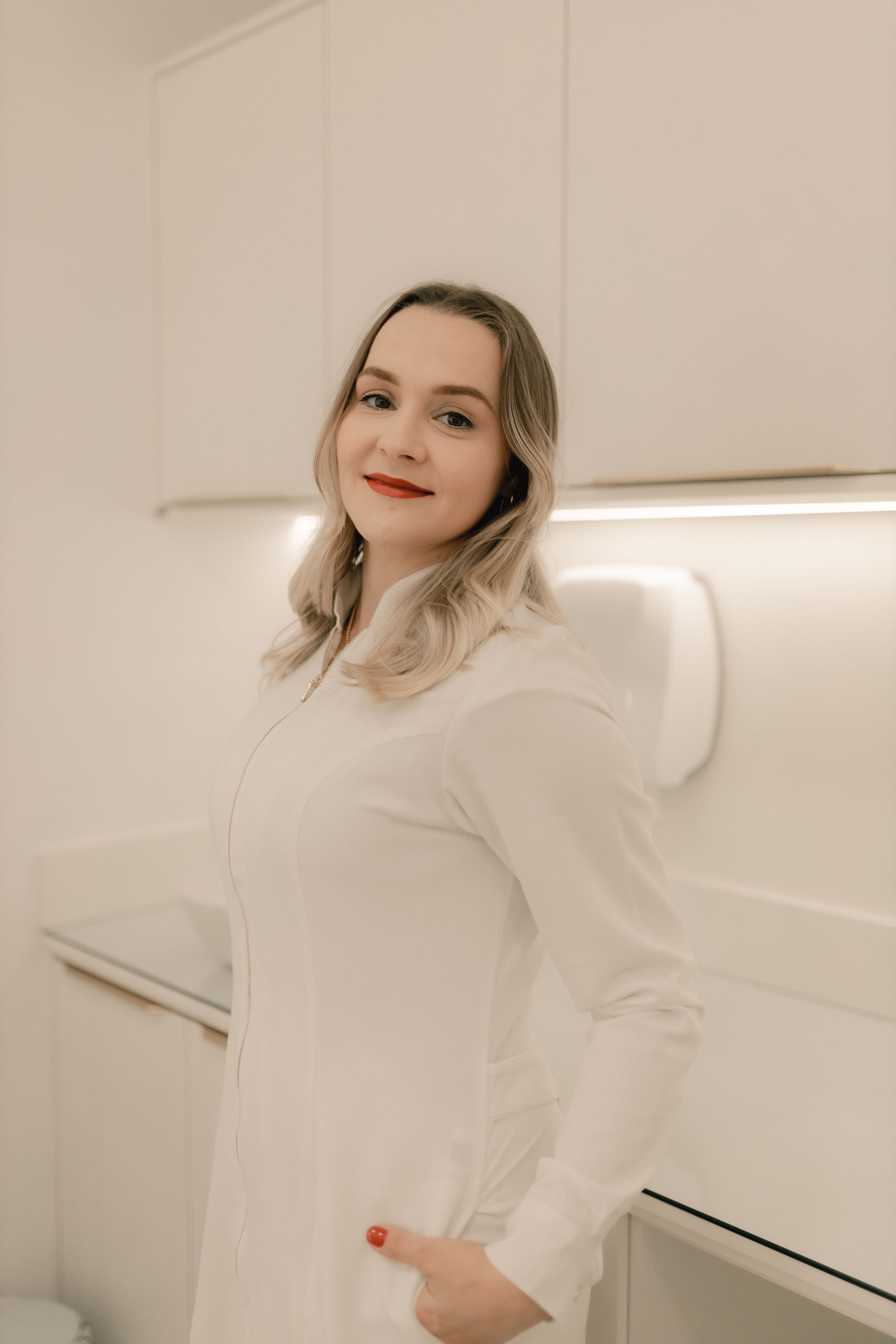 Portrait of a smiling woman in white in a bright, modern office.
