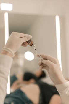 Healthcare worker preparing syringe with medicine vial in clinical environment.