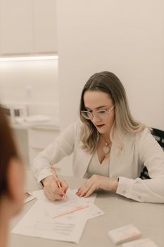 Woman in an office setting writing on paper, emphasizing professionalism and focus.