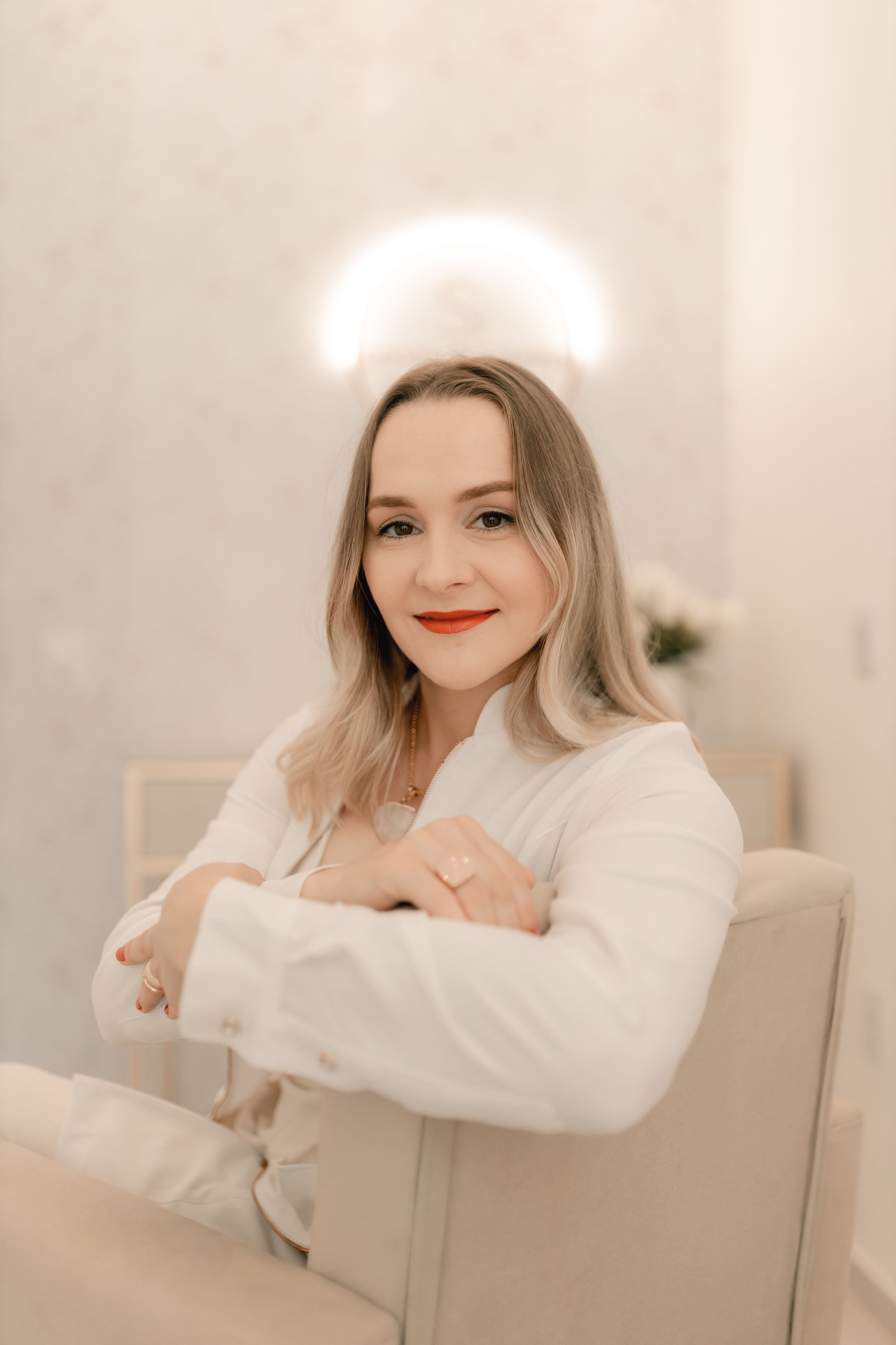 Elegant portrait of a confident woman sitting indoors with a soft smile.