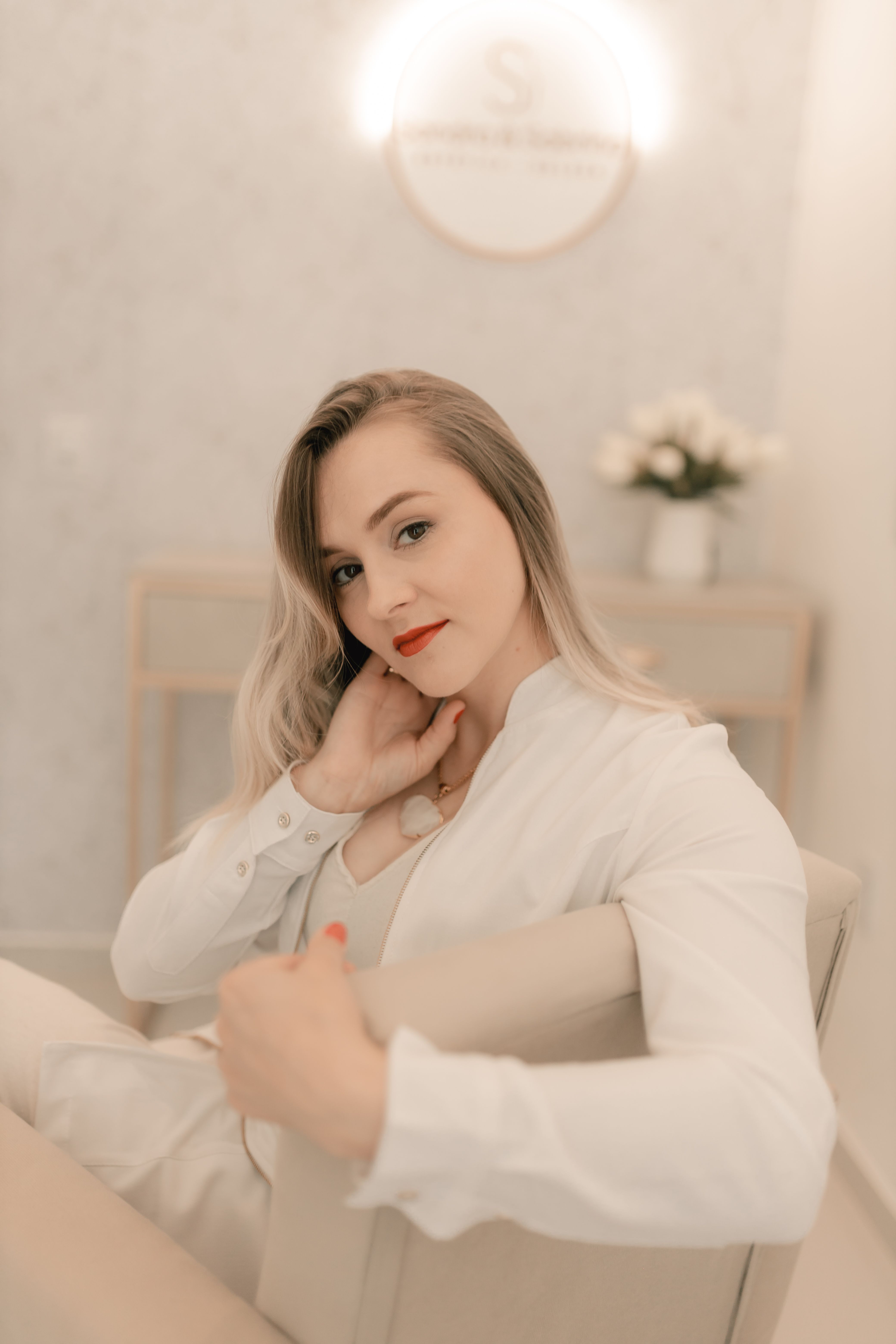 Sophisticated portrait of a woman with red lips in a soft, minimalist space.