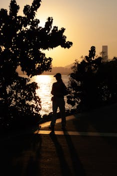 Silhouette of a person by the water during sunset in Shenzhen, China.