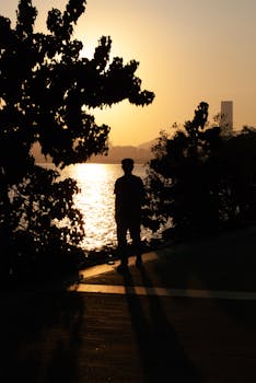 Silhouette of a person by the water with sunset in Shenzhen, China.