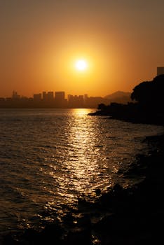 Stunning sunset view over Shenzhen's skyline with shimmering ocean reflections.