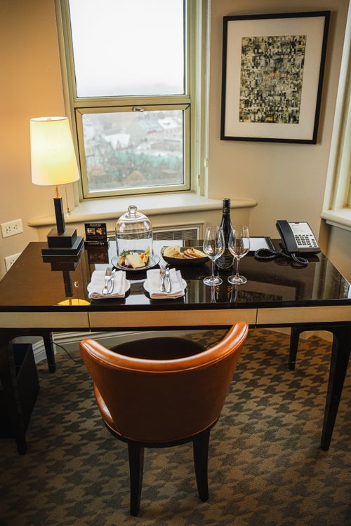 Free A luxurious hotel room with a dining setup near a window overlooking Québec City, offering a sophisticated ambiance. Stock Photo