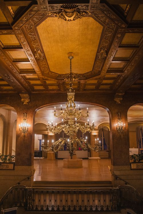 Free Ornate chandelier and opulent decor in a grand hotel lobby captured in warm lighting. Stock Photo