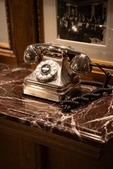 A classic rotary dial telephone placed on a glossy marble countertop indoors.