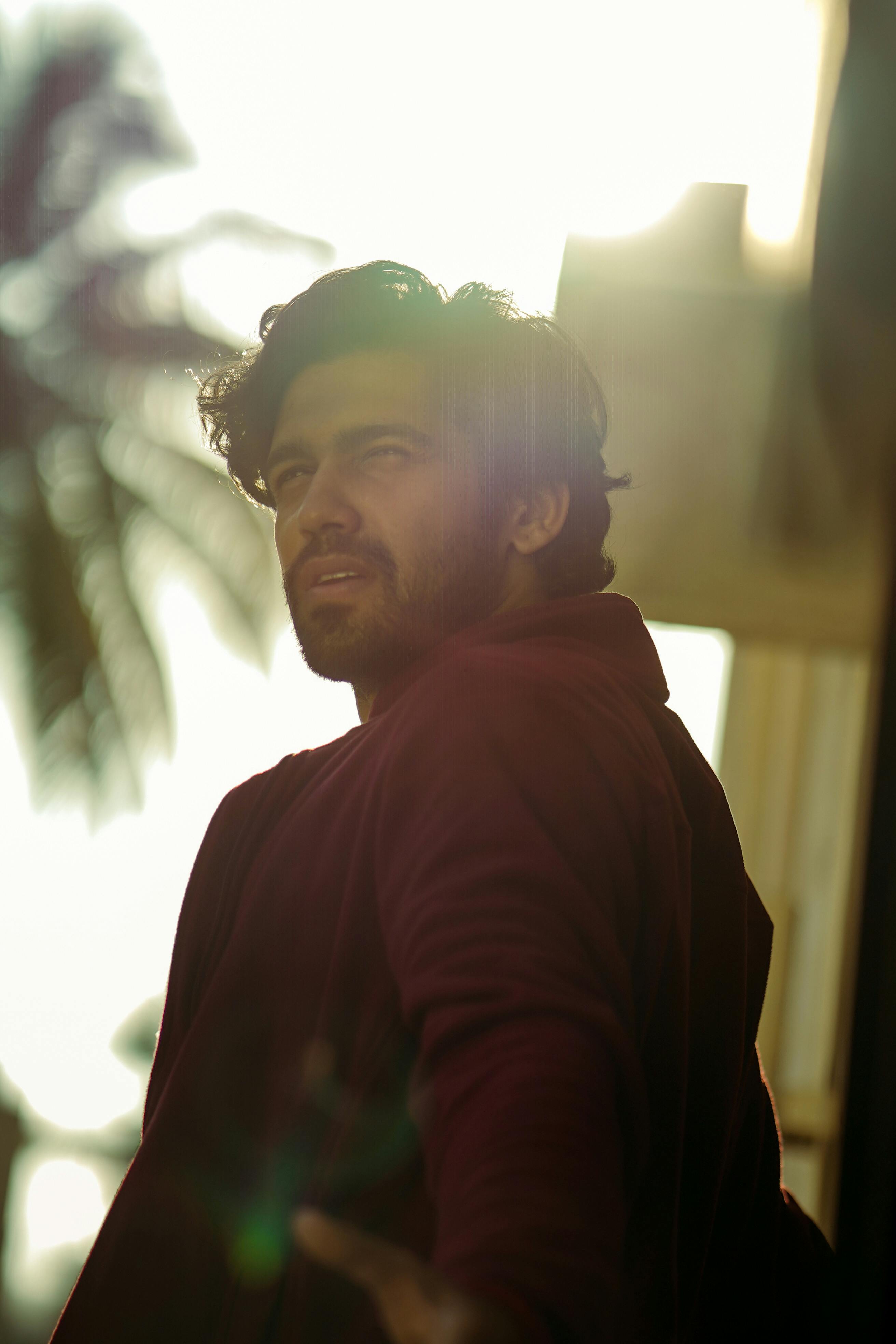 Man looking upward outdoors with dramatic sunlight effect.