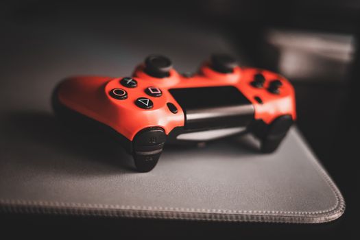 Red gaming controller on desk, highlighting ergonomic design and sleek appearance.