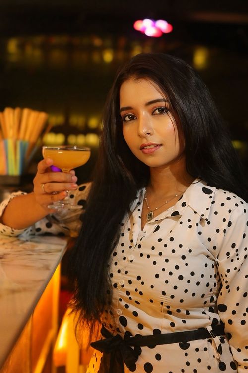 Free Chic woman in polka dot dress holding a cocktail at a bar. Stock Photo