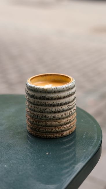 Close-up of a textured ceramic cup on a green outdoor table. Perfect for rustic charm themes.