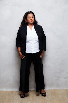 Portrait of a confident woman in professional business attire posing against a neutral indoors background.