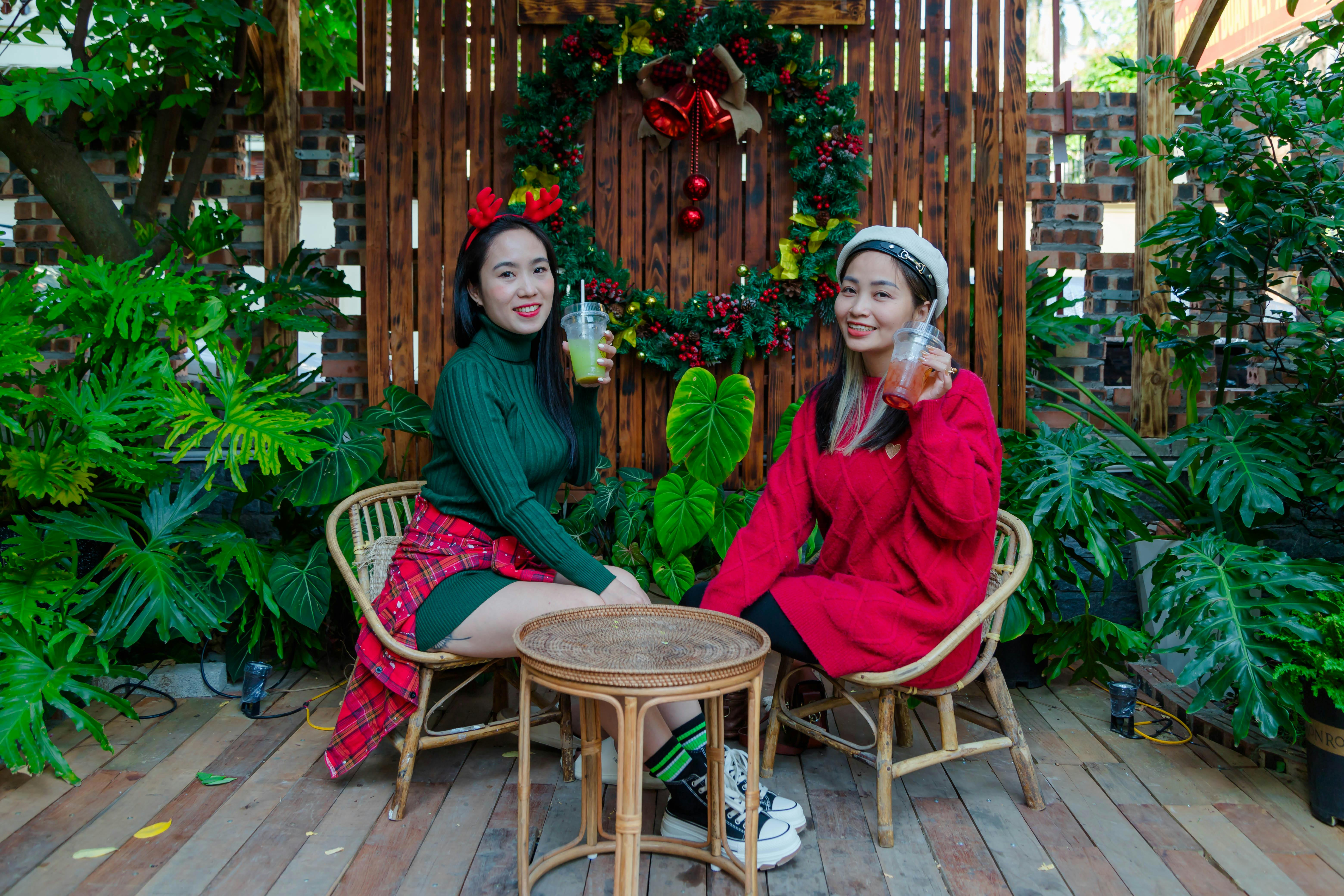 Two women celebrating Christmas in Hải Phòng with festive outfits and drinks.