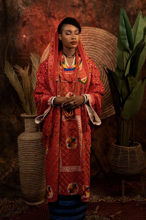 Free A woman in vibrant red traditional clothing with woven baskets and plants. Stock Photo
