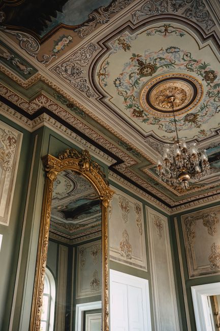 Elegant vintage room with an ornate ceiling and gold mirror reflecting classic design.