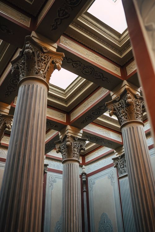 Free Intricately designed classical columns in a historical architectural interior captured from below. Stock Photo