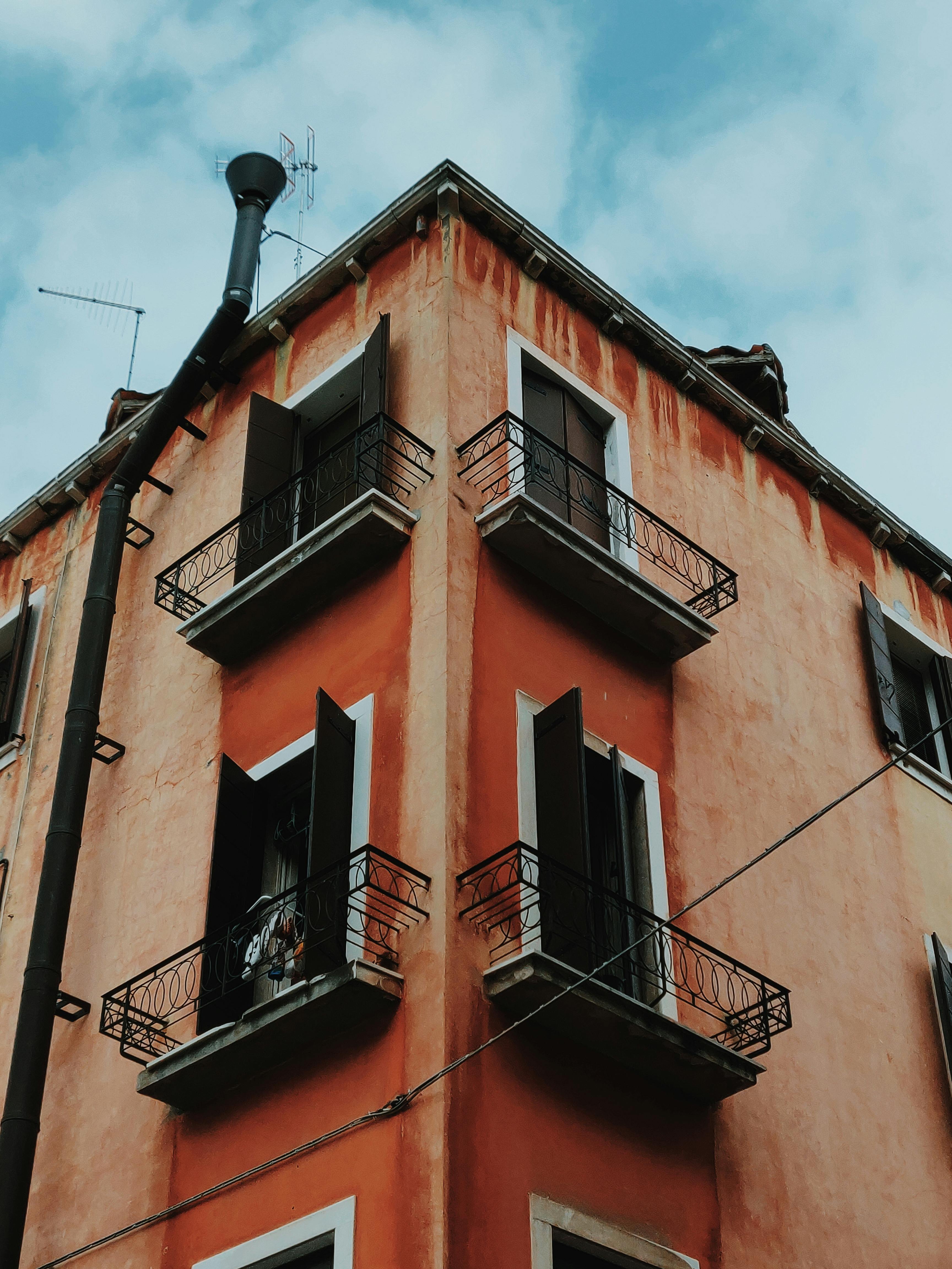 从低角度看去，老式公寓楼的窗户敞开着，阳台映衬着蓝天