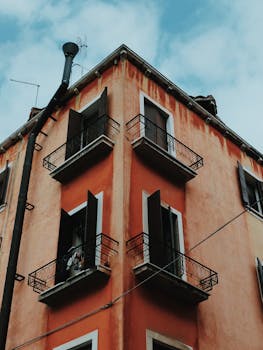 从低角度看去，老式公寓楼的窗户敞开着，阳台映衬着蓝天