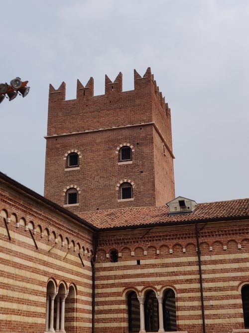 Free A scenic view of a historic brick tower with distinctive arched windows and decorative battlements. Stock Photo