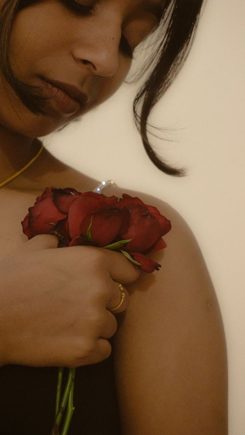 Free A serene portrait of a woman gently holding red roses, conveying warmth and elegance. Stock Photo