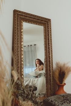 Woman reflected in ornate mirror in cozy indoor space, São Paulo.