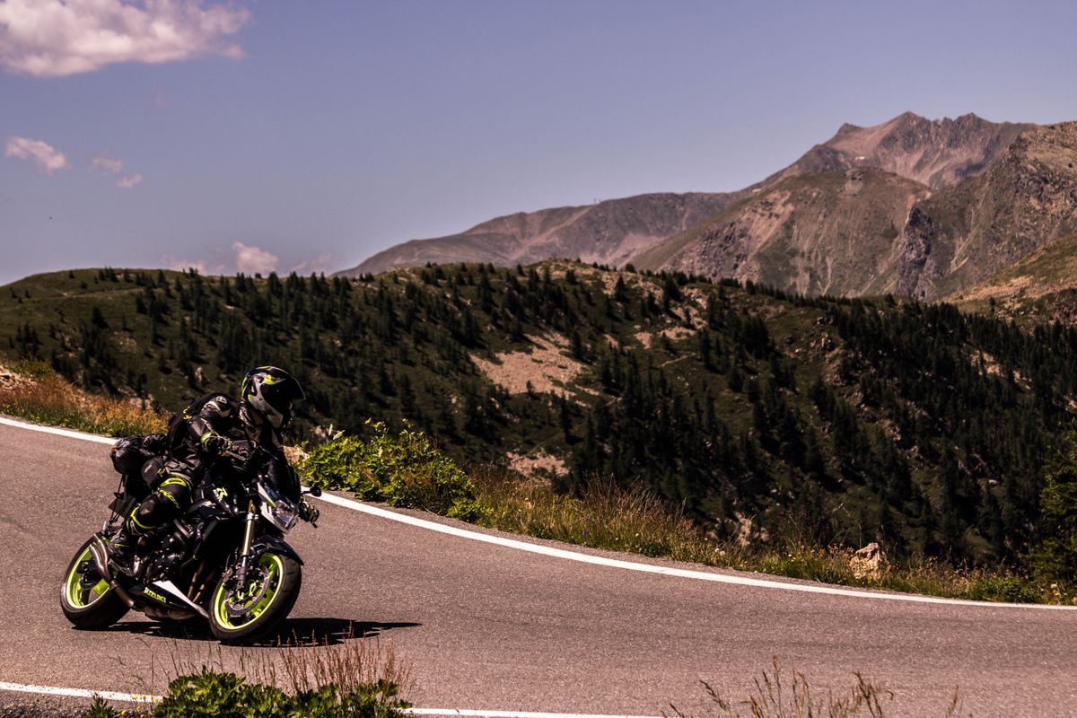 Motociclist inclinat intr-o curba stransa pe drum alpin