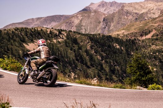 A motorcyclist cruises through the scenic roads of Italy's mountainous landscape, enjoying the adventure and freedom.