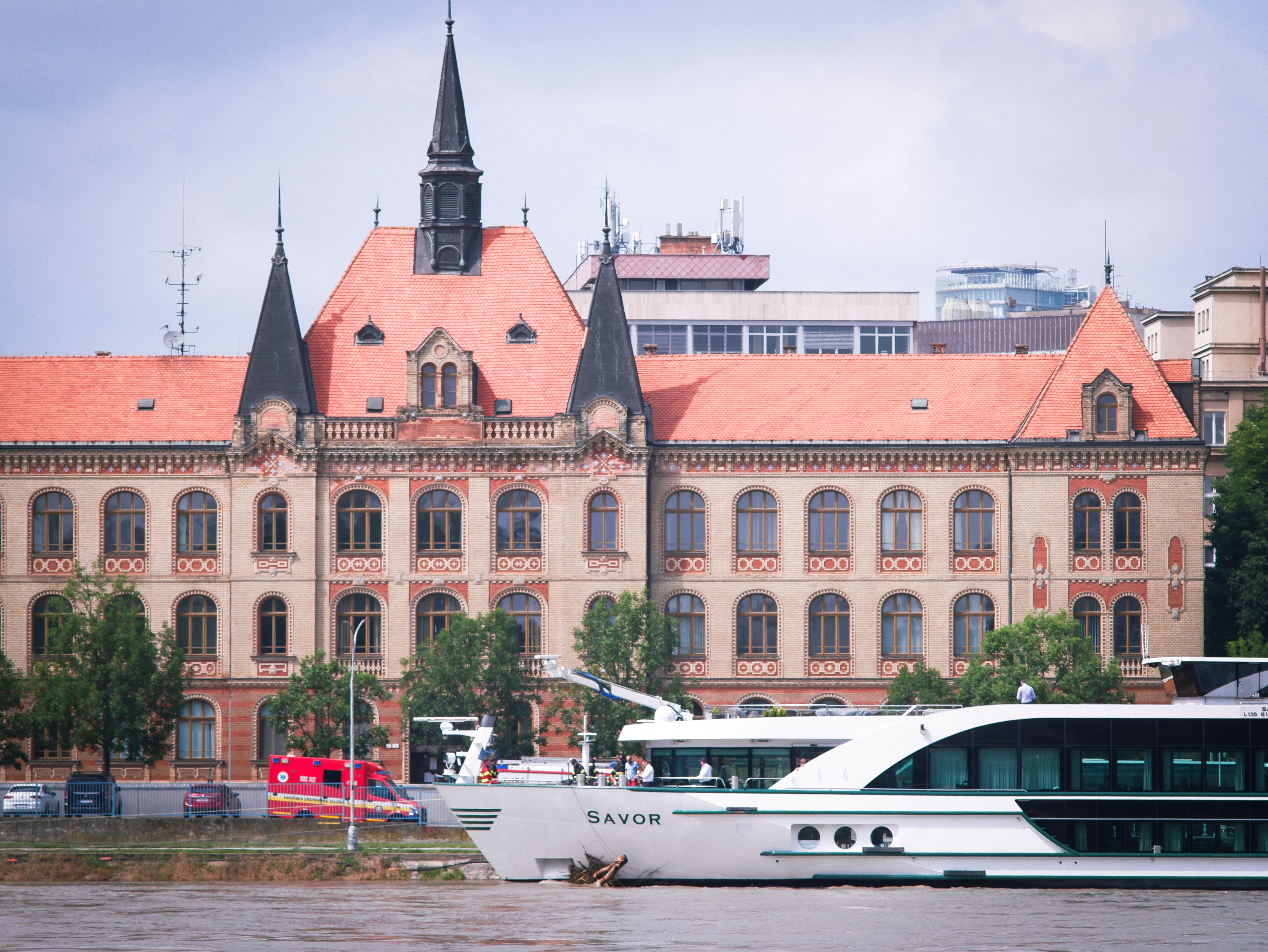 A historic building with ornate architecture riverside in Bratislava. Scenic view with modern vessel nearby.