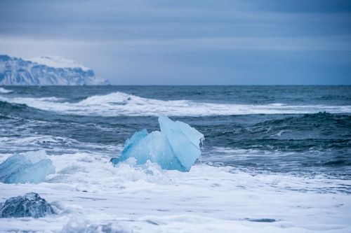 Free Icebergs on the scenic Diamond Beach in Iceland with rugged coastline and ocean waves. Stock Photo