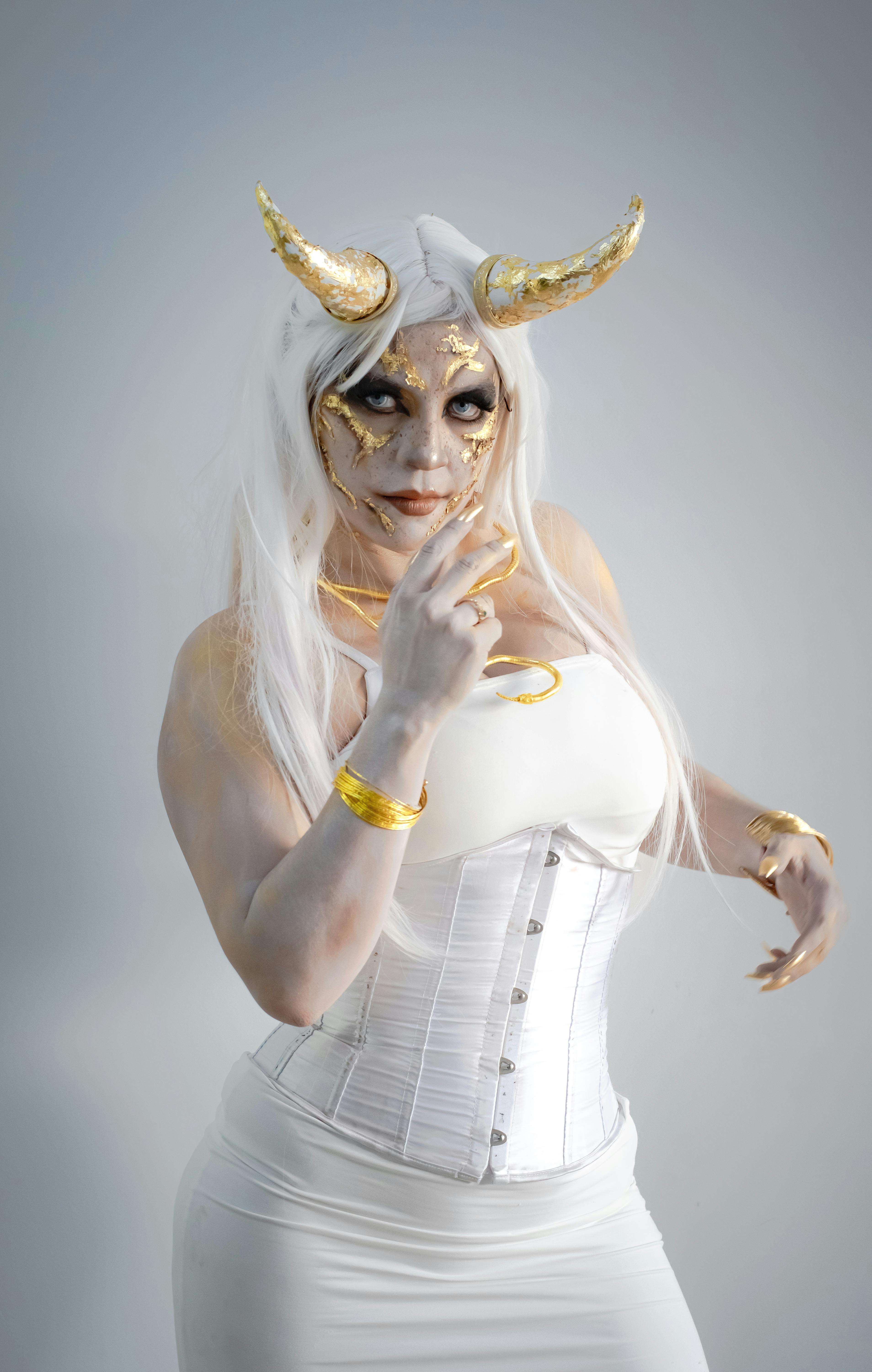 Gratuit Portrait de personnage fantastique représentant une femme aux cornes dorées et au maquillage détaillé, dégageant une allure mystique. Photos