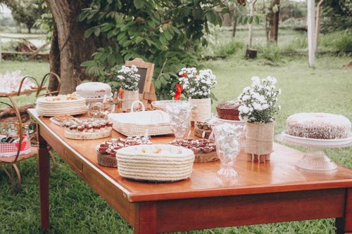 Free An inviting rustic dessert table set outdoors with various cakes and floral decorations. Stock Photo