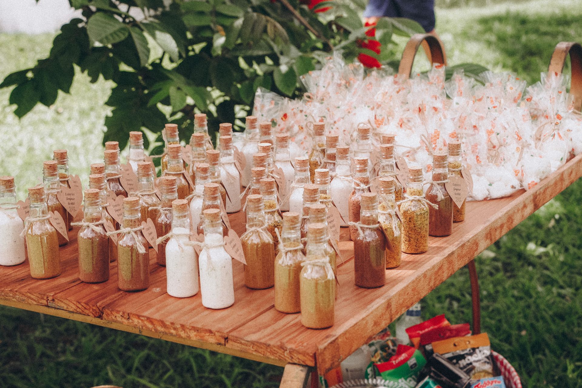 Variety of spices in corked bottles displayed on a wooden table outdoors.