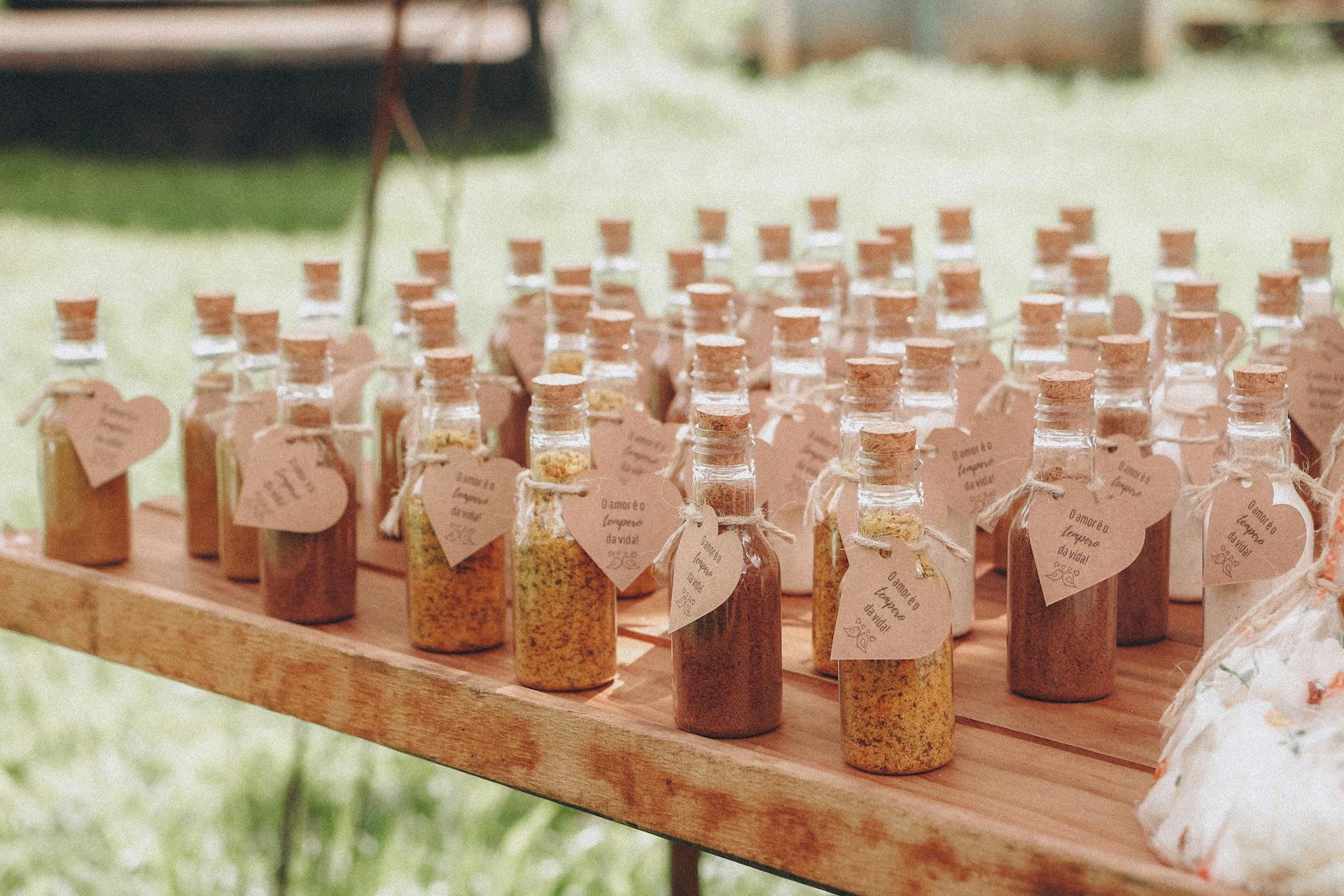 Assorted spice bottles with cork stoppers displayed outdoors on a wooden table with vintage labels.