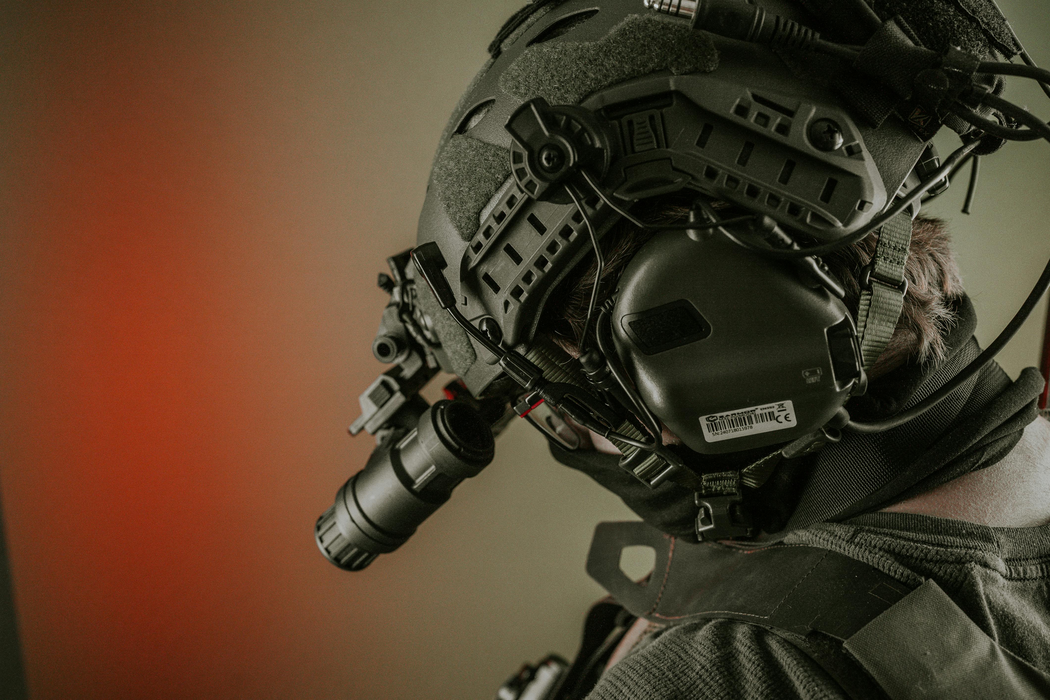 Close-up of a person wearing advanced tactical gear and helmet for military use, with night vision attachment.