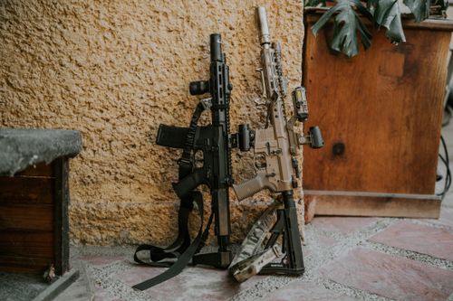 Free Two tactical rifles leaning against a rustic wall, showcasing military equipment. Stock Photo