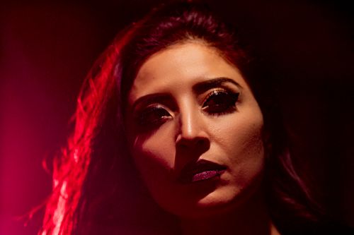 Free An artistic portrait of a woman with dark, dramatic lighting and vibrant color contrast. Stock Photo