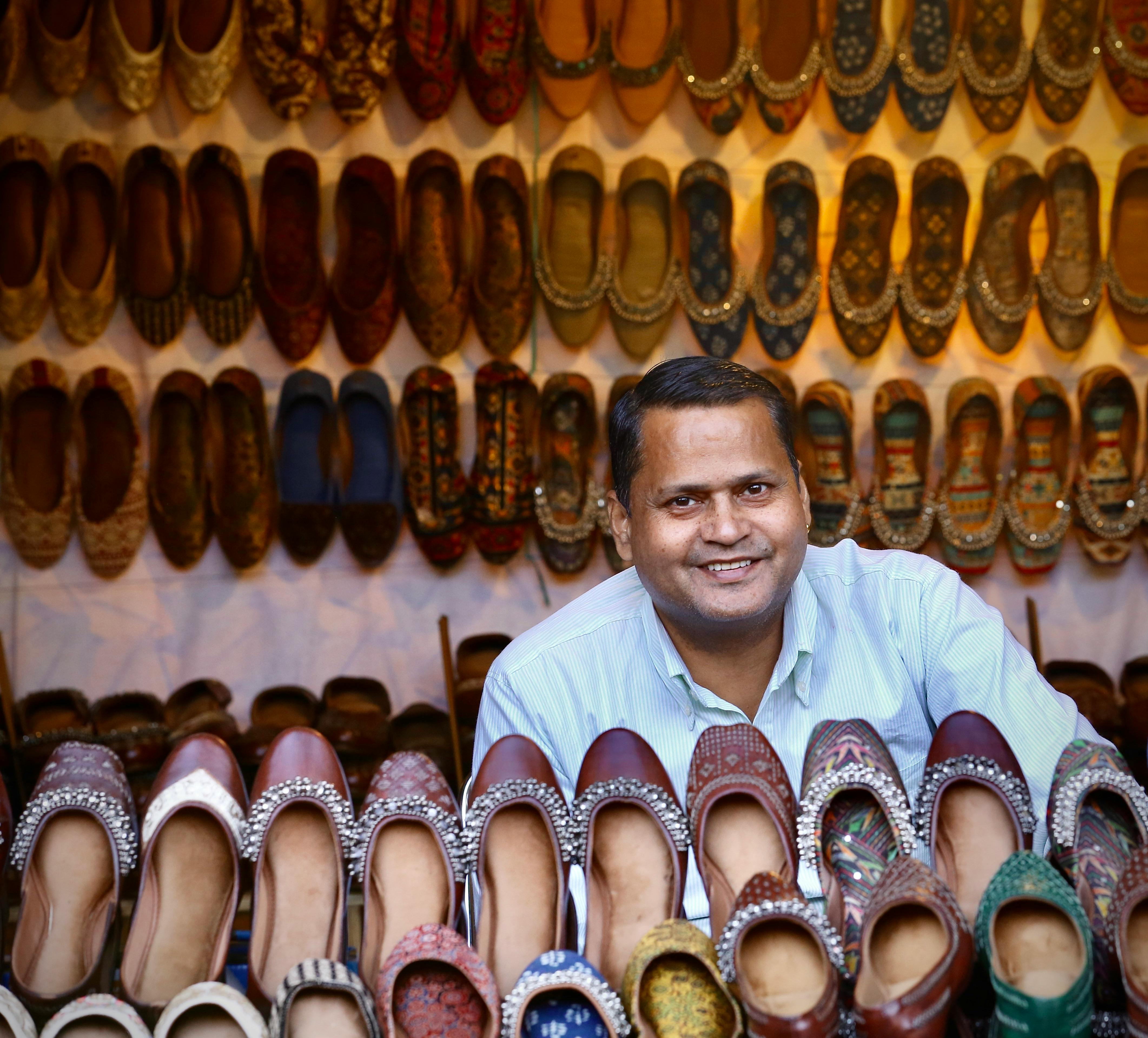 smiling shopkeeper with traditional shoes display