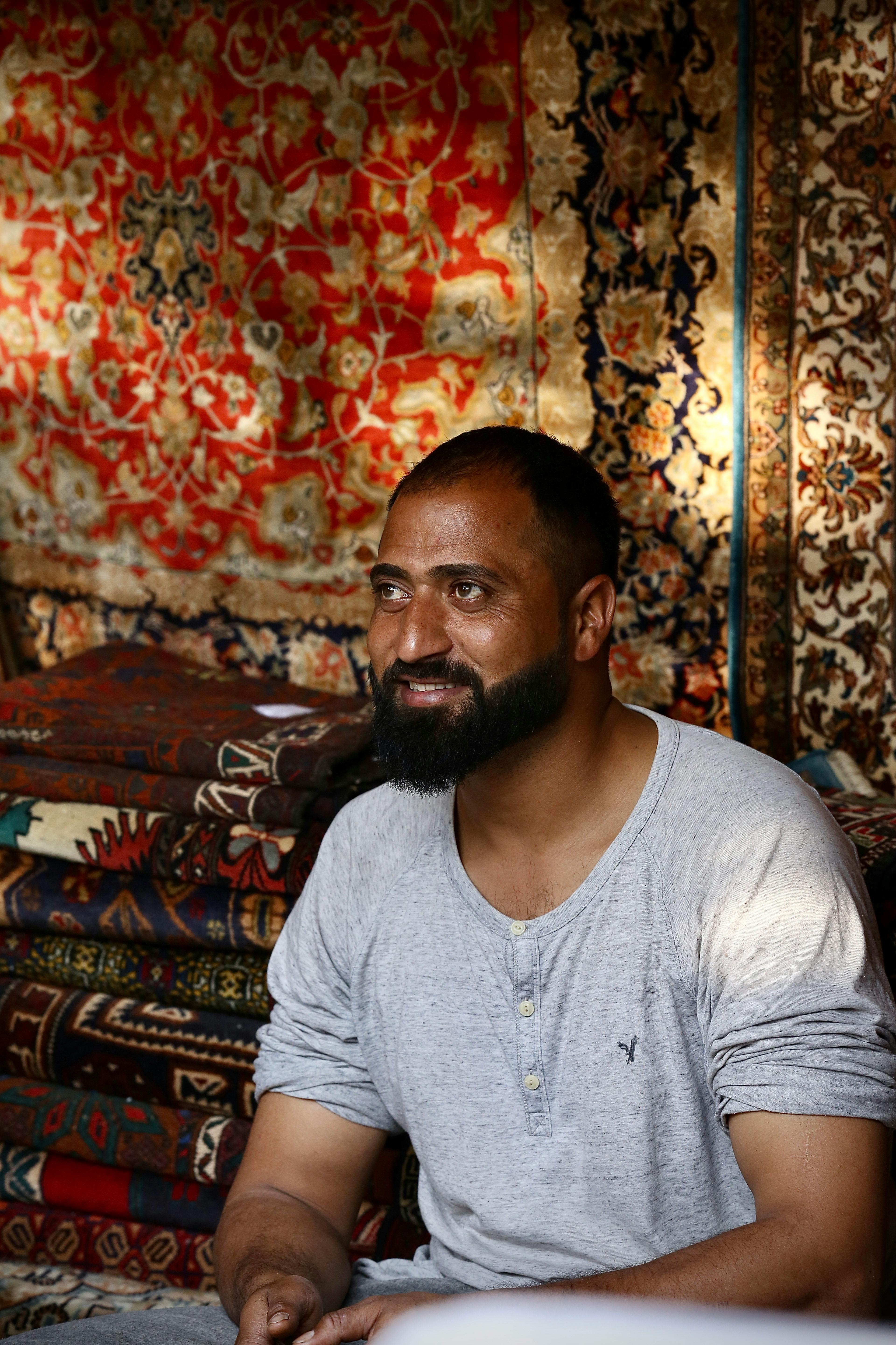 middle eastern man surrounded by colorful rugs