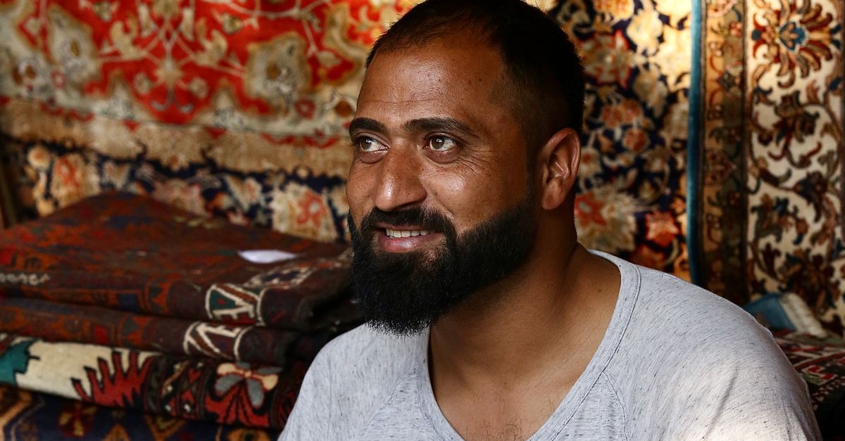 Middle Eastern Man Surrounded by Colorful Rugs · Free Stock Photo